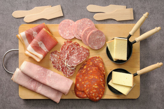 Overhead View of Meats and Cheese for Raclette on Cutting Board on Grey Background, Studio Shot