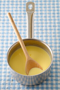 Overhead View of Vanilla Sauce and Wooden Spoon in Cooking Pot on Blue Gingham Background, Studio Shot