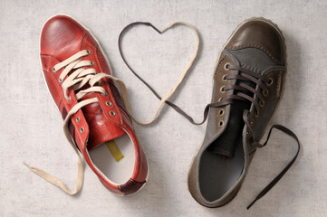 A man's shoe and a woman's shoe with laces tied together in a heart shape