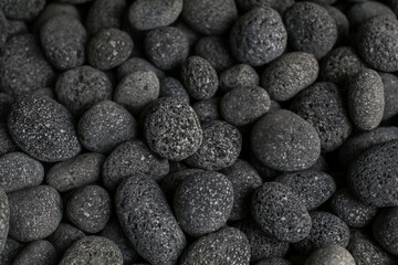 Abstract background of black pebble stones on the floor. Smooth round pebbles texture wallpaper.