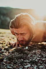 Muscular modern guy doing push-ups on top of mountain in nature