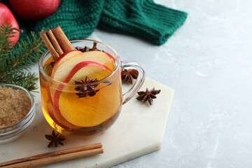 Aromatic hot mulled cider on light grey marble table. Space for text