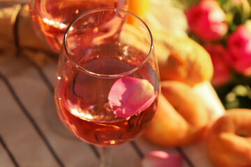 Glass of delicious rose wine with petals and peaches outside, closeup