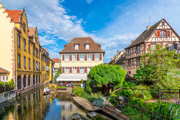 Colorful half timbered buildings and waterfront cafes on the Lauch River in the historic medieval Little Venice district of Colmar, France, in the Alsace region.	