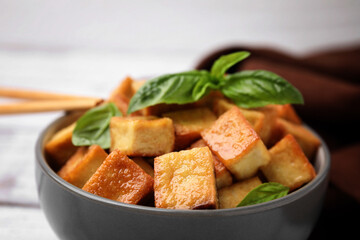 Bowl with delicious fried tofu and basil, closeup