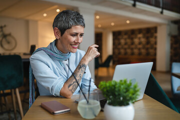 One woman mature adult senior female work on laptop at cafe