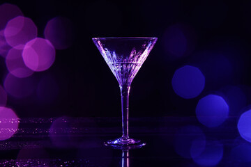 Martini glass and splashes in neon lights on dark background, bokeh effect