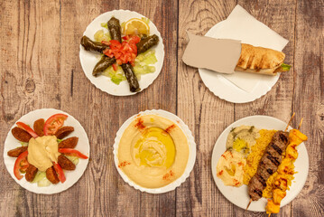 Set of dishes from super popular Middle Eastern food recipes with chickpea hummus with paprika and oil, stuffed vine dolmas, falafel fdrito, a shawarma and grilled chicken and lamb kebab skewers