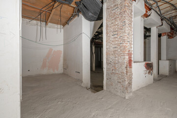 Rough premises with all exposed unfinished electrical piping and cement floors, brick pillars and...