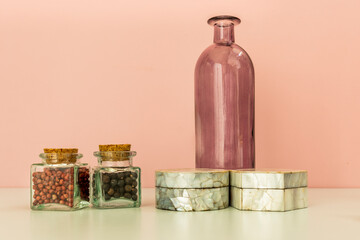Some glass jars with spices and others made of mother-of-pearl and a fuchsia bottle on a blue table