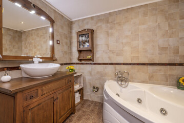 Bathroom with porcelain sink on country-style wood cabinet and quarter-circle whirlpool tub
