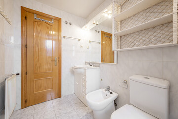 Fototapeta na wymiar Bathroom with white porcelain sink with marble top and white wooden cabinet with drawers, mirror with matching sconces and wooden shelf