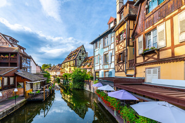 Fototapeta na wymiar View of half timber homes and cafes from a boat on the Lauch canal in the historic medieval Petite Venice district of Colmar, France, in the Alsace region.