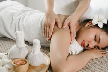 Obraz na płótnie Canvas Relaxed pretty asian young woman enjoying remedial body massage done by professional masseur in spa room