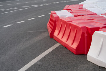 Temporary road barriers installed on asphalt with intermittent markings to prevent accidents or...