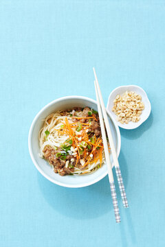 Overhead View of Noodles with Pork, Peanuts, and Shredded Carrot in Bowl with Chopsticks