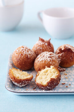 Mini cake donuts with powdered sugar on a blue platter
