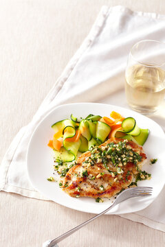 Grilled Chicken Breast topped with peanut and spinach relish, served with zucchini and carrot ribbons with a glass of white wine