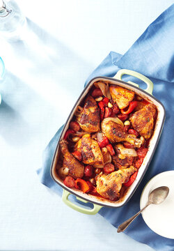 Pan of roasted chicken pieces with tomato, onion, and red peppers