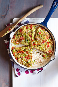 Sesame rice omelette with red peppers and green onions in an enamel skillet