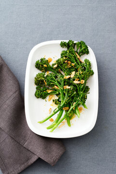Chinese broccoli with fried garlic and almonds on a white platter