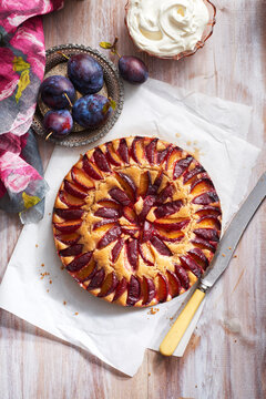 Plum cake with fresh plums and whipped cream and serving knife