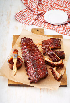 BBQ ribs with barbeque sauce and brush on a cutting board with parchment paper