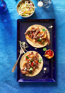 Beef Tacos on a blue platter with a side dish of coleslaw