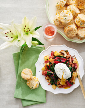 Poached egg on vegetables on fancy plate served with chedder herb scones