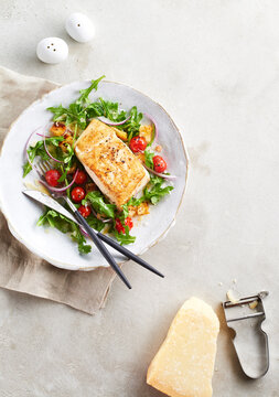 Halibut with arugula and cherry tomato salad served with shaved parmesan cheese