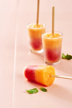 Homemade fruit ice pops with mint on a peach background