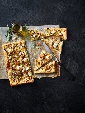 Zucchini, goat cheese and walnut tart on parchment paprer on a black background