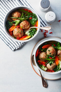 Bowls of Asian chicken meatballs in broth with vegetables