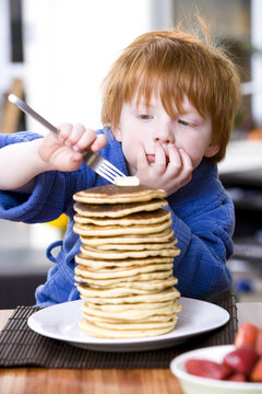 Little Boy Eating a Stack of Pancakes