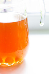 A decanter of orange fruit juice stands on the windowsill, and round sugar candies lie at the bottom