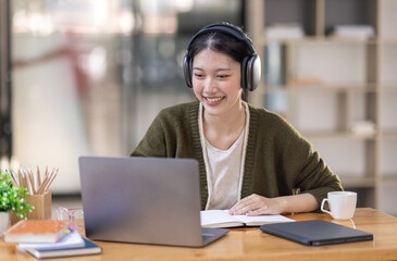 Young adult happy smiling Hispanic Asian girl student wearing headphones talking on online chat...