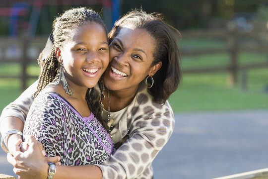 Portrait of pre-teen girl and mother, hugging outdoors
