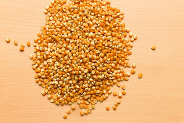 Pile of yellow corn seeds isolated on brown wooden background, for popcorn.