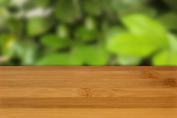 bamboo table view with blurred green leaves bokeh perspective background.