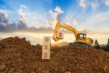Fototapeta Concept Happy new year 2023,crawler excavator of lift up bucket that is installing the number three. obraz