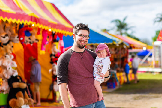 Portrait of a young dad with baby at country showground sideshow alley