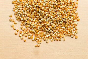 Pile of yellow corn seeds isolated on brown wooden background, for popcorn.