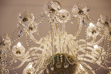 Luxury expensive chandelier hanging from the ceiling in the apartment. Crystal chandelier in the room. Close-up