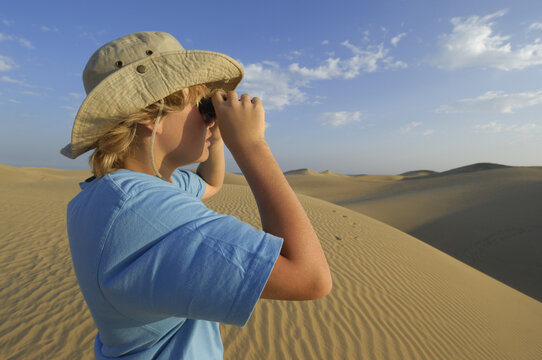 Boy Looking Out Over Sand Dunes Through Binoculars, Playa del Ingles, Cran Canaria, Canary Islands