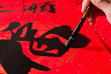 writing spring festival couplets to celebrate Chinese new year holidays.(the write word meaning...