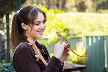 Happy teen with two pet bearded dragon lizards in garden