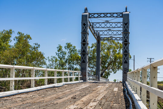 Bitumen covered boards and white railings leading across an old lift span bridge