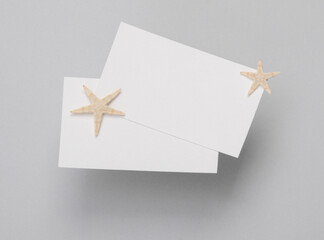 Fototapeta na wymiar White Blank business cards for branding and starfishes on gray background. Creative Mockup for presentations and corporate identity. Travel Company. Top view