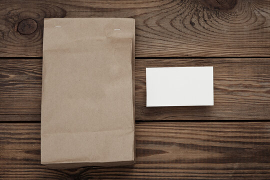 Craft packaging mockup and white business card for branding on wooden table