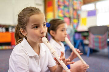 Two Schoolgirls Playing Recorder in Classroom